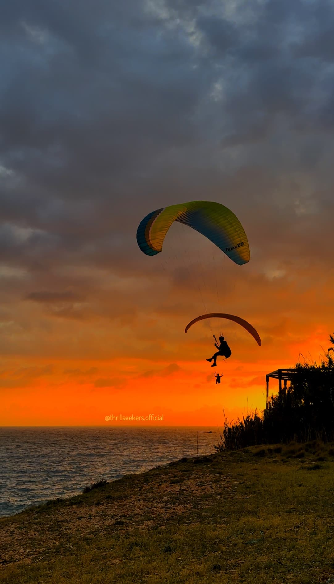 Two paragliders at sunset over Lebanese coastal cliffs